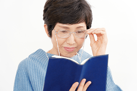 老眼鏡をかけて本を読む女性