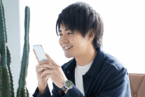 画面を顔に近づけた状態でスマートフォンを使用する男性