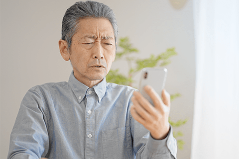 スマートフォンを見にくそうにしている男性