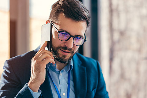 仕事で電話をかけているメガネを掛けた男性