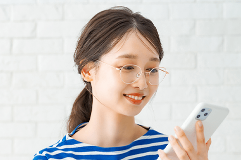 メガネをかけてスマートフォンを操作する女性
