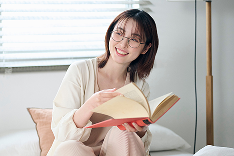 部屋のなかでメガネをかけて本を読んでいる女性